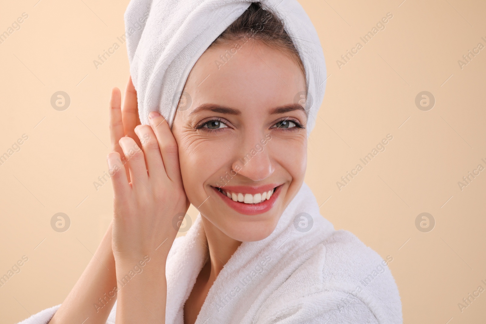 Photo of Beautiful young woman with hair wrapped in towel after washing on beige background