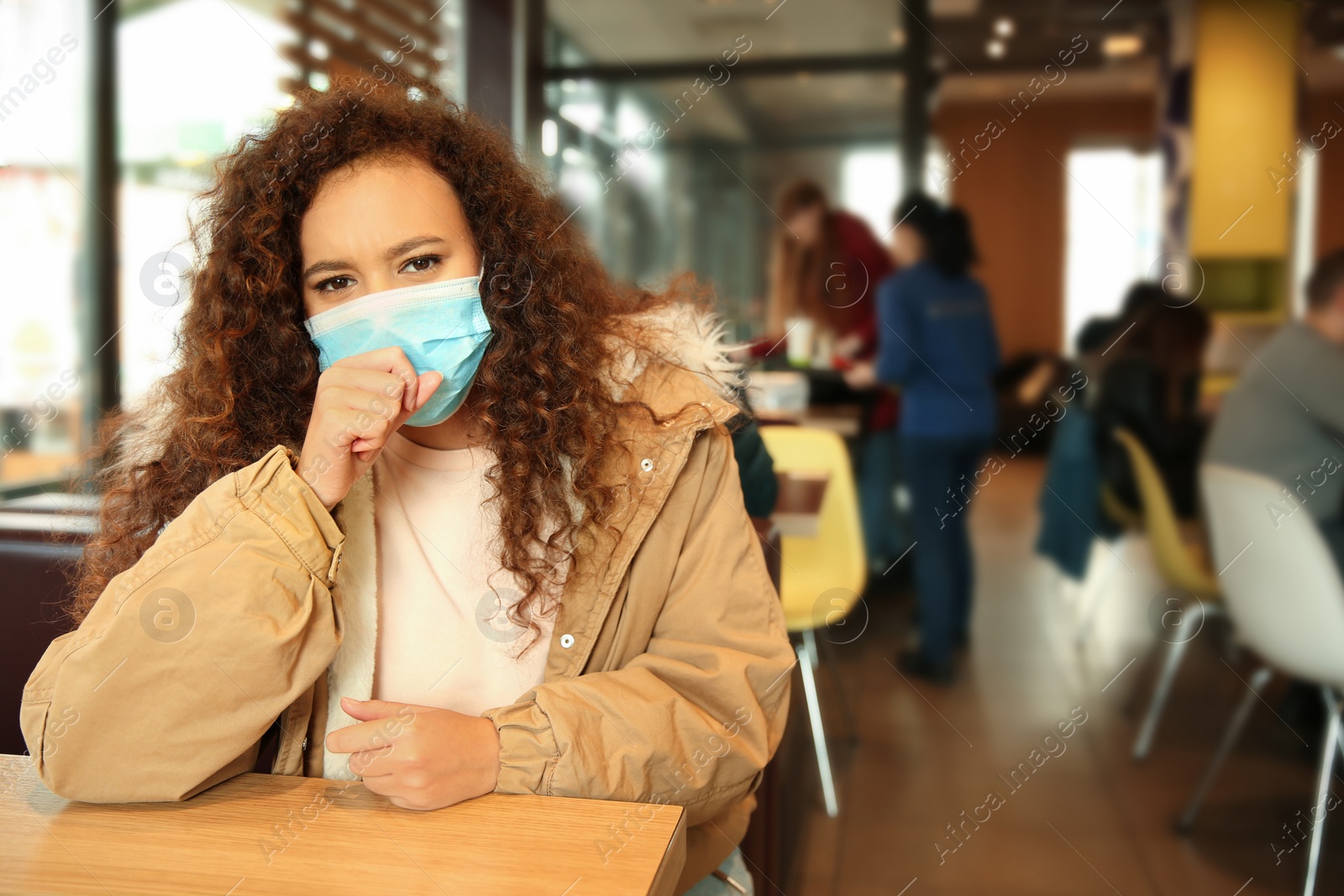 Photo of African-American woman with disposable mask in cafe. Virus protection