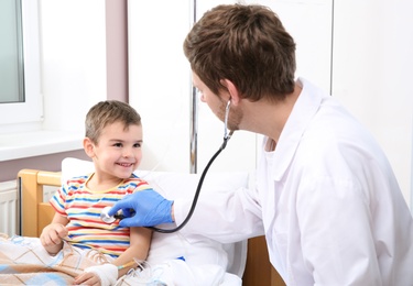 Photo of Doctor examining little child with stethoscope in hospital