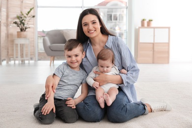 Young mother with her children sitting together on floor at home