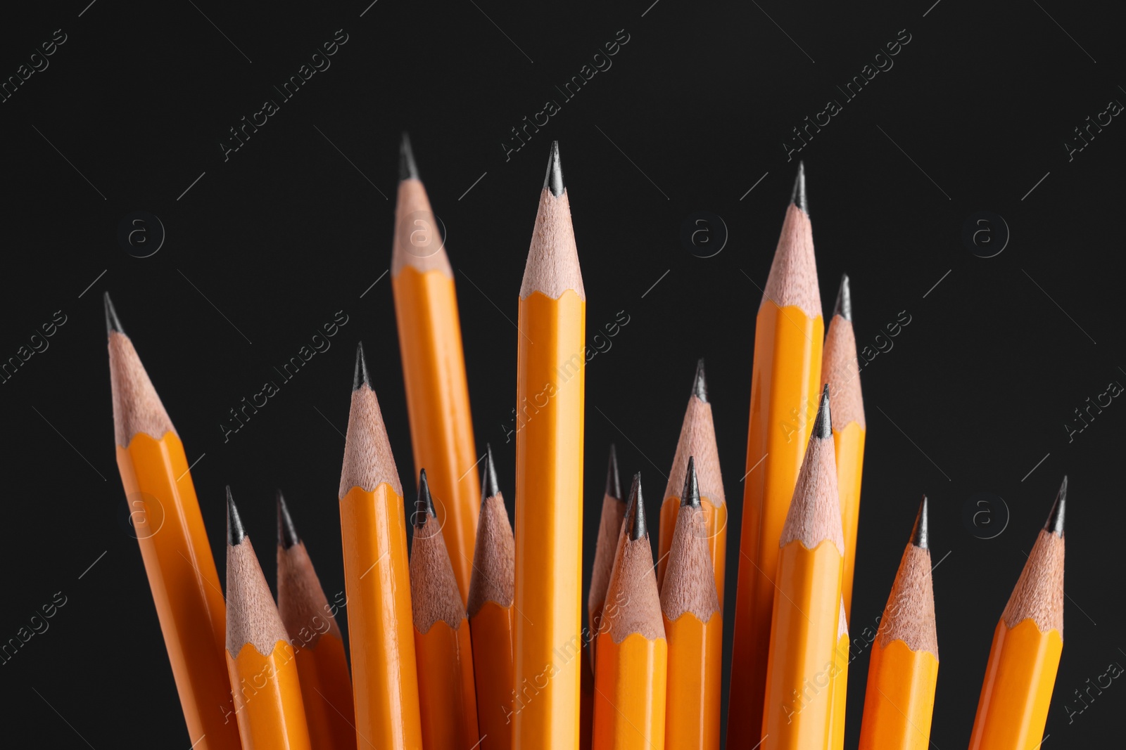 Photo of Many graphite pencils on black background, closeup