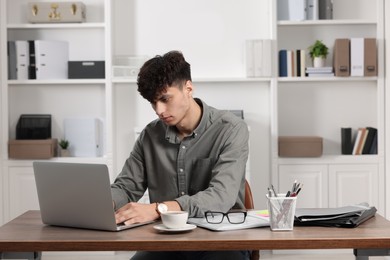 Photo of Young man working at white table in office. Deadline concept