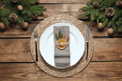 Photo of Festive place setting with beautiful dishware, fabric napkin and dried orange slice for Christmas dinner on wooden table, flat lay