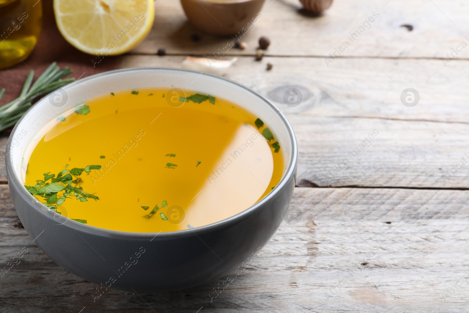 Photo of Bowl with lemon sauce on wooden table, space for text. Delicious salad dressing