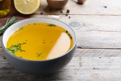 Bowl with lemon sauce on wooden table, space for text. Delicious salad dressing