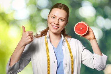 Nutritionist with grapefruit on blurred green background