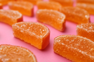 Photo of Delicious orange marmalade candies on pink background, closeup