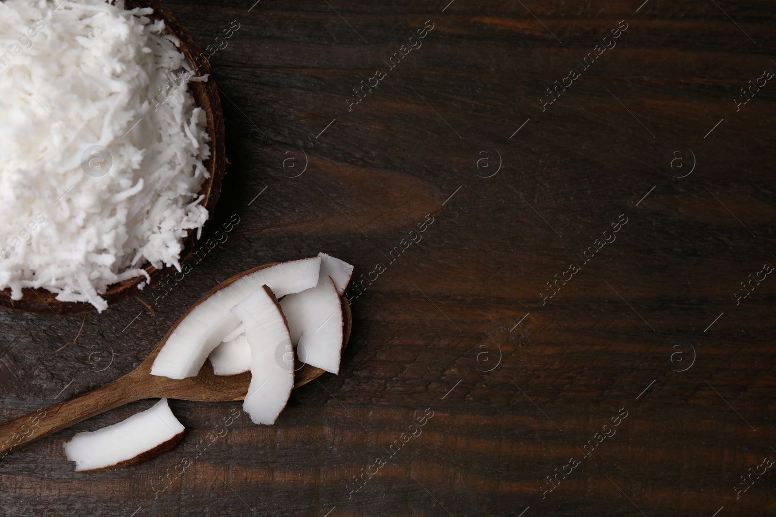 Photo of Coconut flakes, spoon and nut on wooden table, top view. Space for text