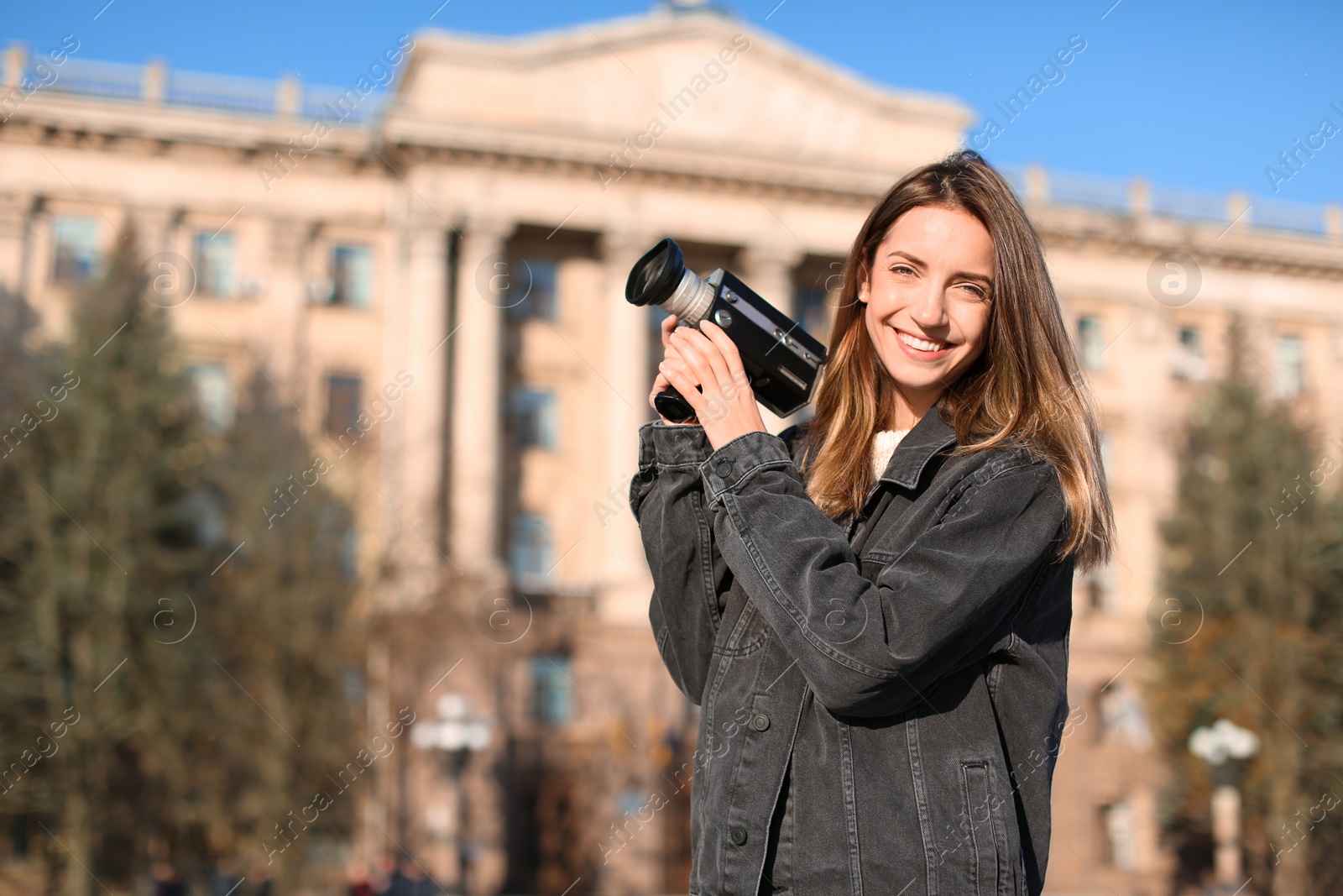 Photo of Beautiful young woman with vintage video camera on city street