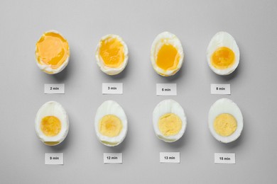 Different cooking time and readiness stages of boiled chicken eggs on light grey background, flat lay