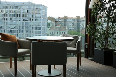 Photo of Observation area cafe. Table, armchairs and green plant on terrace against beautiful cityscape