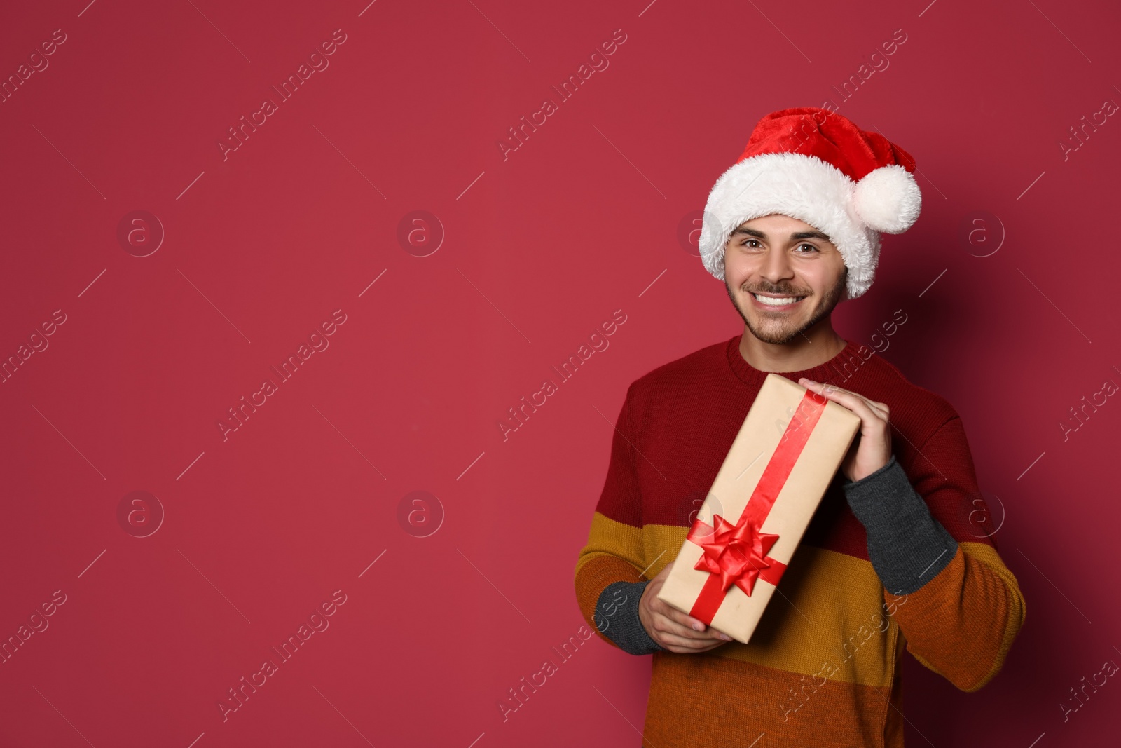 Photo of Young man with Christmas gift on color background