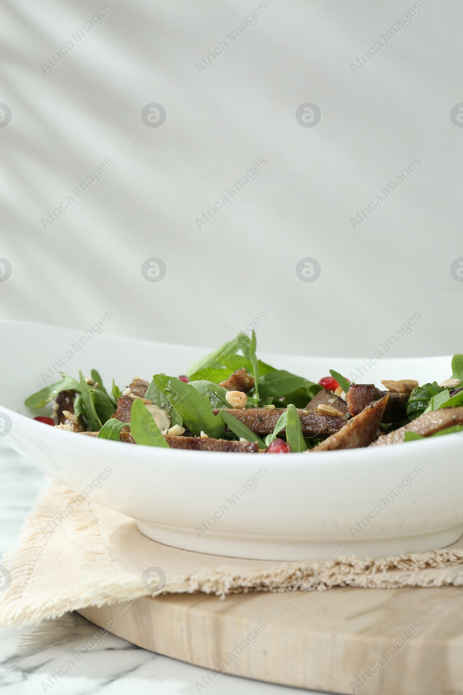 Photo of Delicious salad with beef tongue, arugula and seeds on white marble table