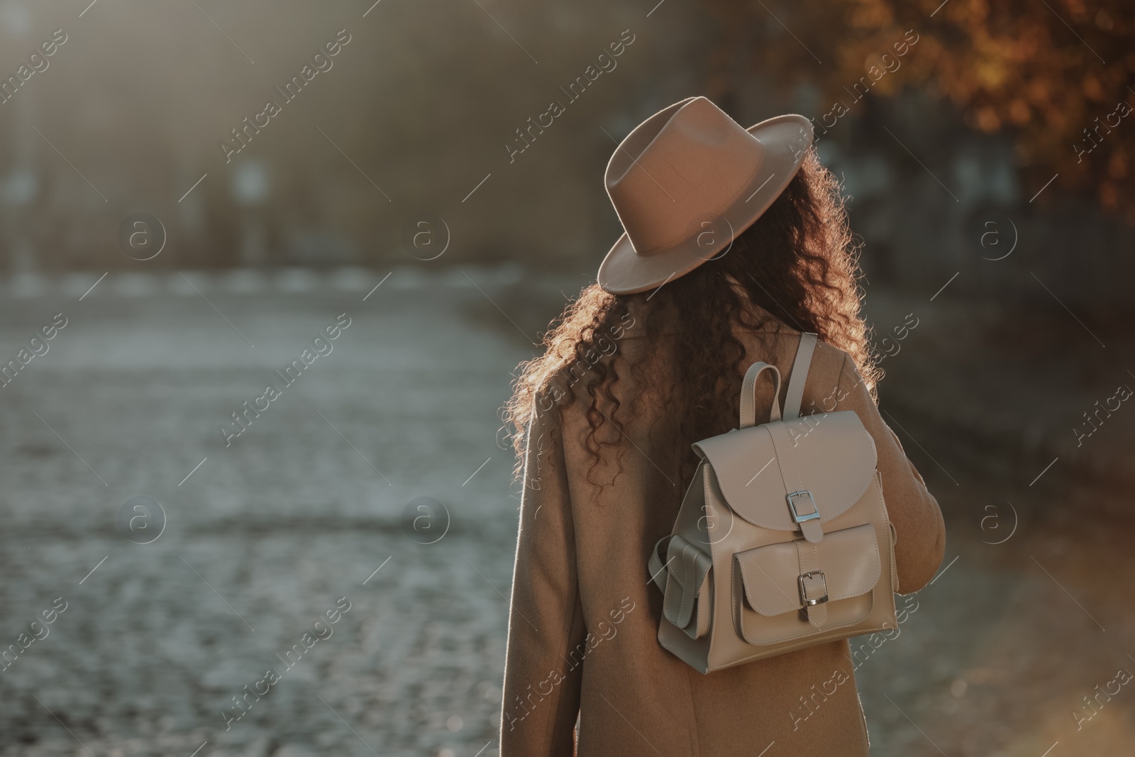 Photo of African-American woman with stylish beige backpack on city street, back view. Space for text