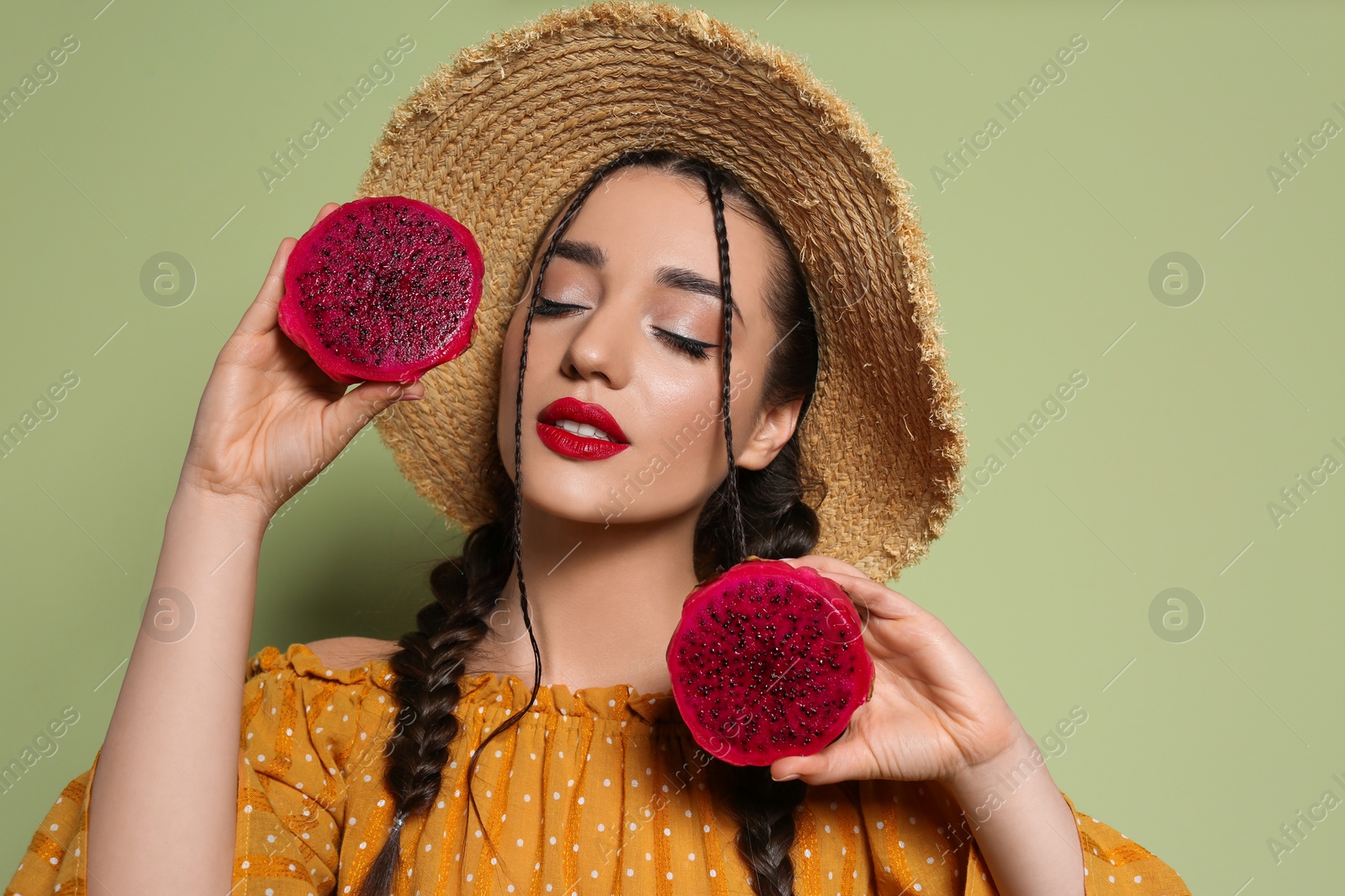 Photo of Young woman with fresh pitahaya on olive background. Exotic fruit