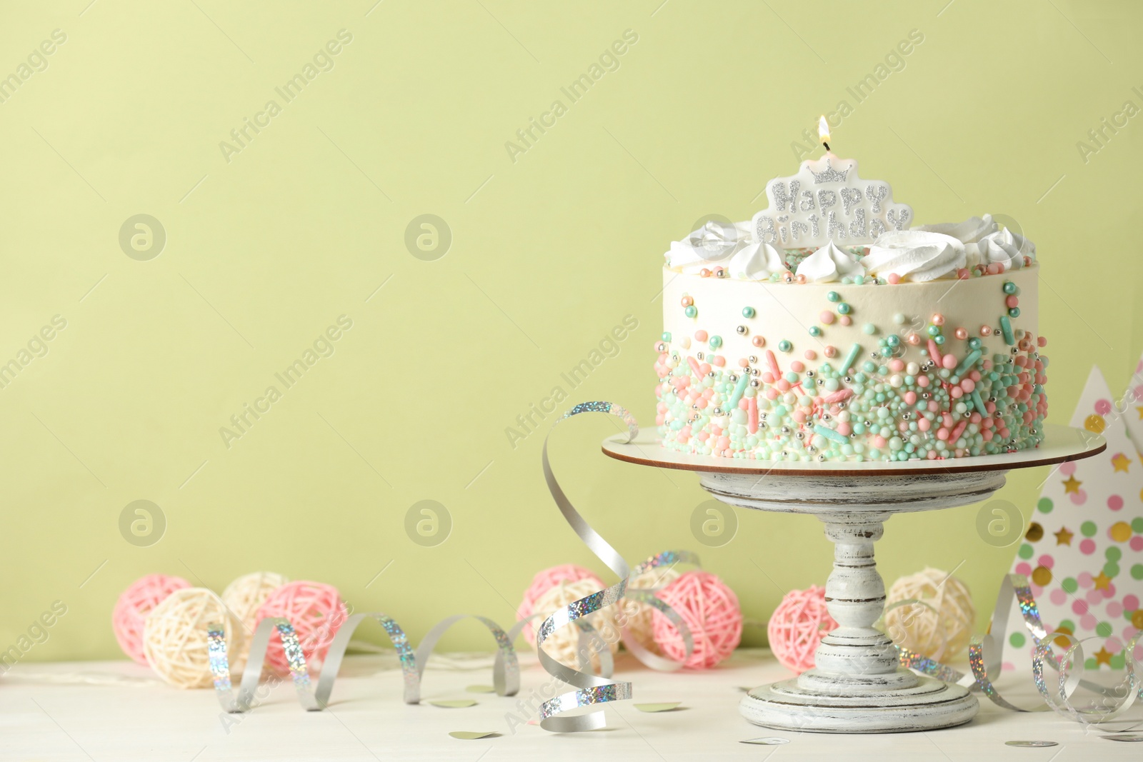 Photo of Delicious birthday cake and party decor on white wooden table against light background, space for text