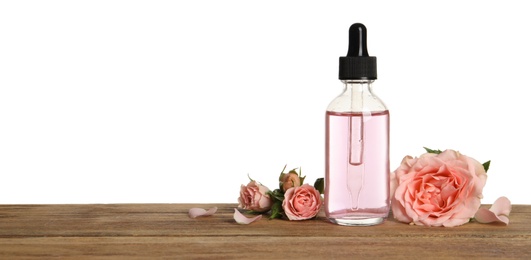 Bottle of rose essential oil and flowers on table, white background