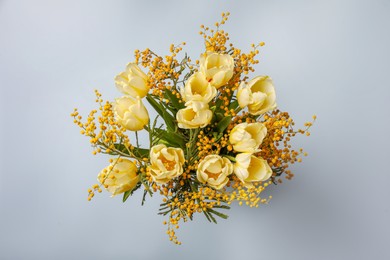 Bouquet with beautiful tulips and mimosa flowers on light grey background, top view