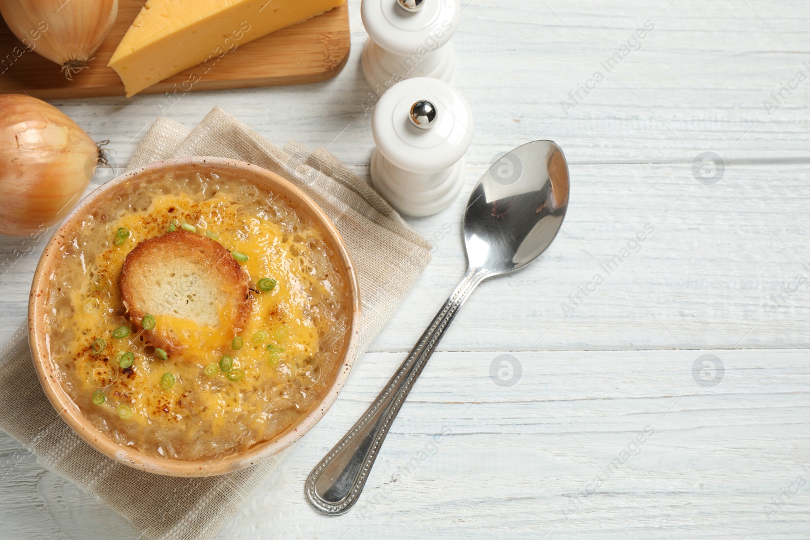 Photo of Tasty homemade french onion soup served on white wooden table, flat lay. Space for text