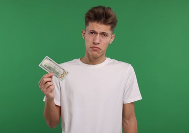 Upset man with dollar banknote on green background