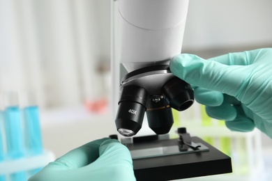 Photo of Medical assistant using modern microscope, closeup