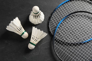 Photo of Feather badminton shuttlecocks and rackets on grey textured table, flat lay