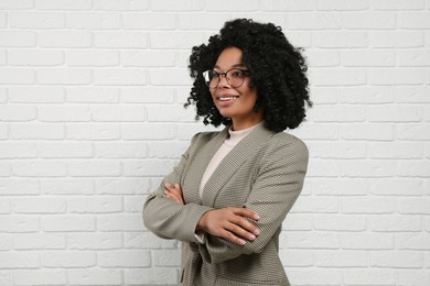 Photo of Young businesswoman in eyeglasses near white brick wall