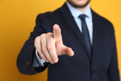 Photo of Businessman touching something against orange background, focus on hand