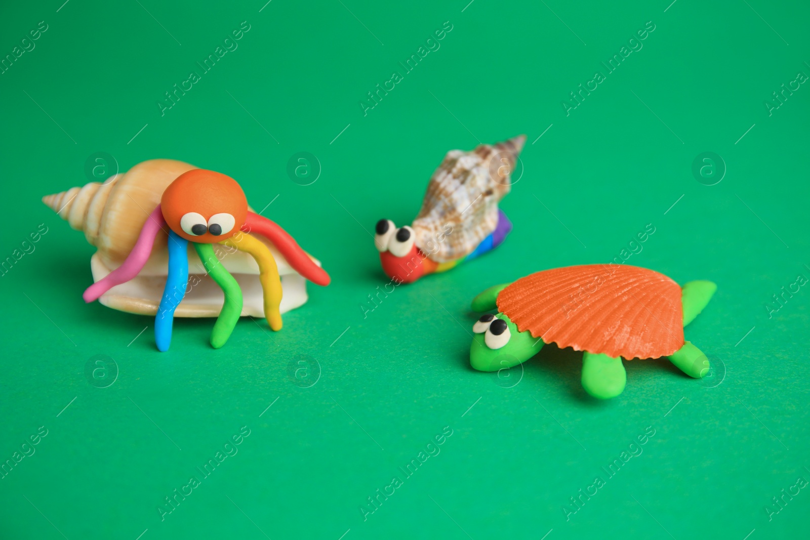 Photo of Turtle, crab and snail made from plasticine on green background. Children's handmade ideas