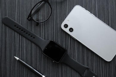 Photo of Flat lay composition with stylish smart watch on black table