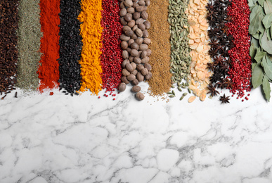 Photo of Many different spices on white marble background, top view. Space for text