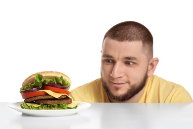 Young man and tasty burger on white background