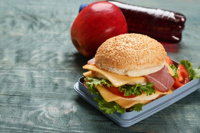 Photo of Lunch box with tasty sandwich on wooden table