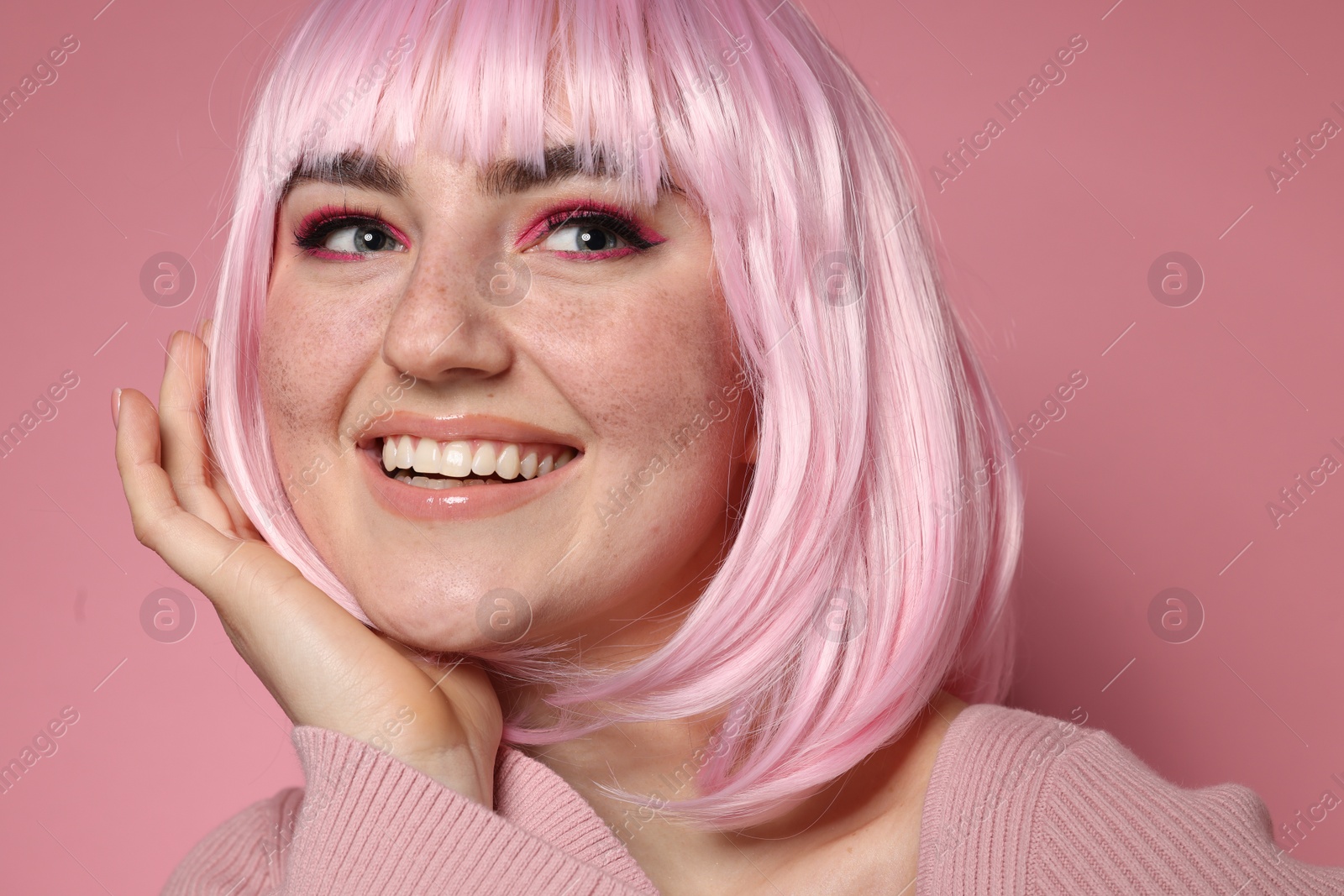 Photo of Happy woman with bright makeup and fake freckles on pink background, closeup