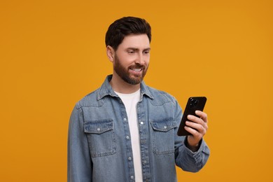 Photo of Smiling man with smartphone on orange background