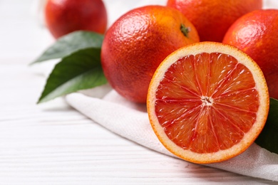 Photo of Whole and cut red oranges on white wooden table, closeup