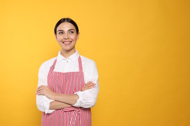 Young woman in red striped apron on yellow background, space for text