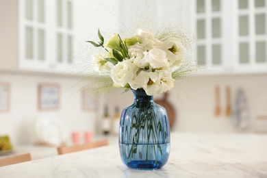 Photo of Bouquet of beautiful eustoma flowers on white table in kitchen. Interior design