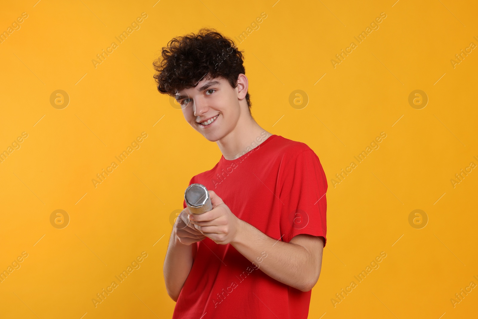 Photo of Portrait of happy teenage boy with party popper on orange background