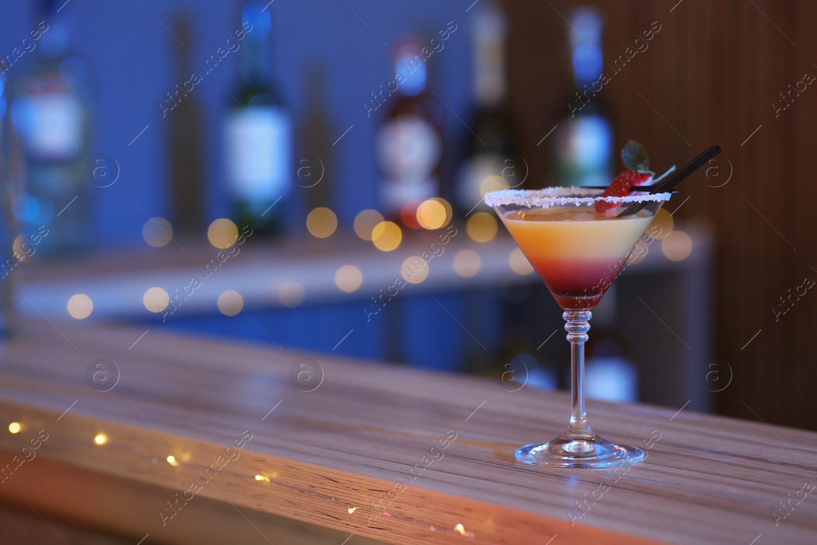 Photo of Delicious strawberry martini cocktail on table in bar, space for text