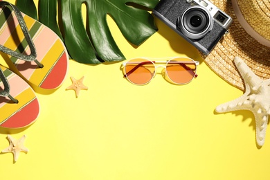 Flat lay composition with beach accessories on yellow background, space for text