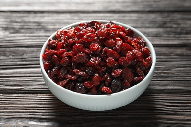 Photo of Bowl with cranberries on wooden table. Dried fruit as healthy snack