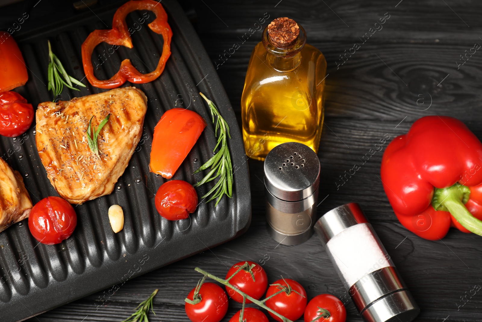 Photo of Electric grill with different products on black wooden table