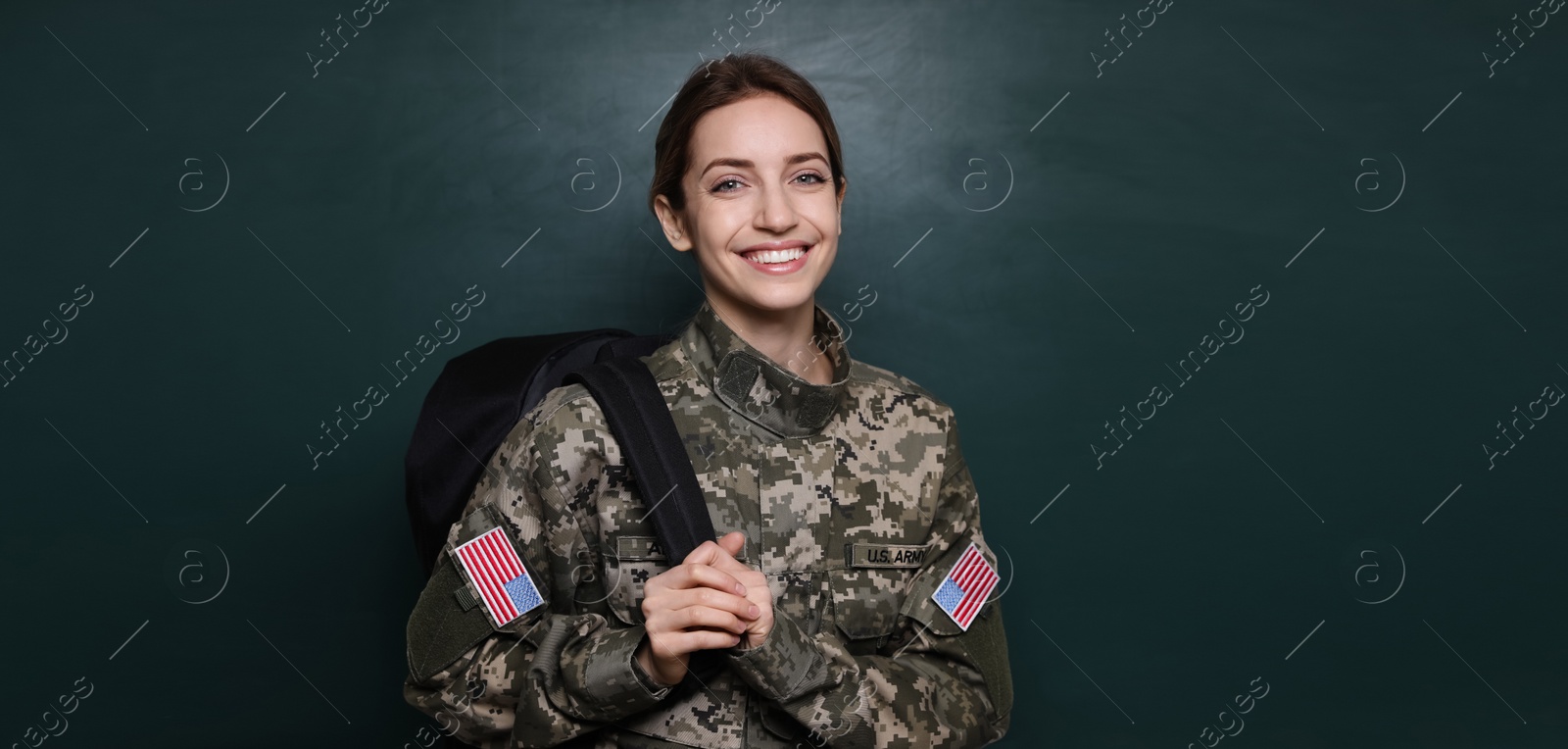 Image of Military education. Cadet with backpack near green chalkboard