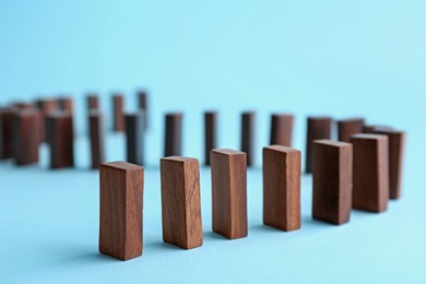 Row of wooden domino tiles on light blue background