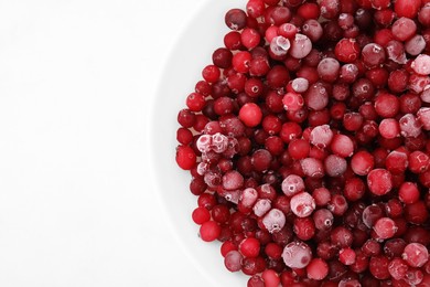 Frozen red cranberries in bowl on white table, top view. Space for text