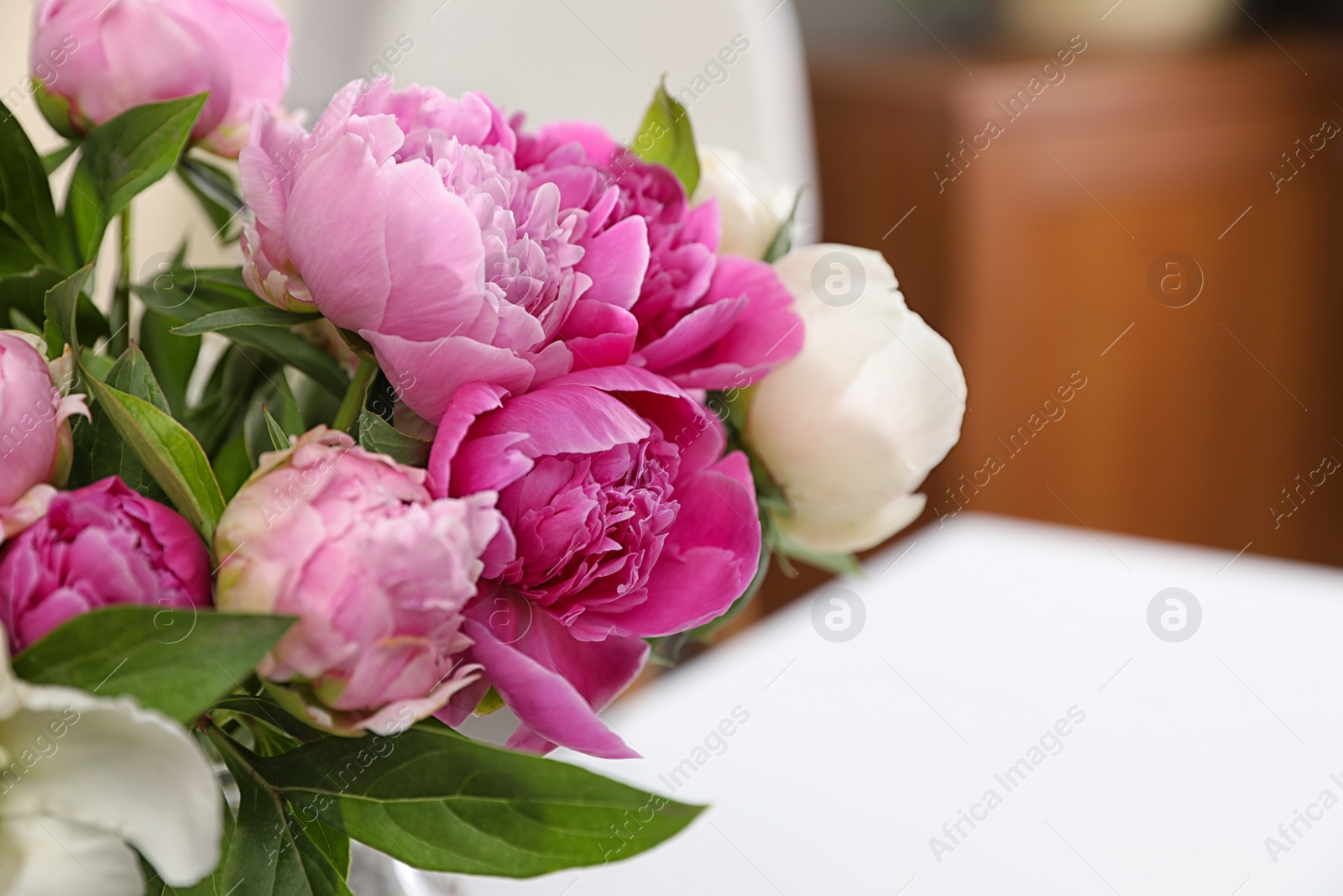 Photo of Bouquet of beautiful peonies on table in room, closeup. Space for text