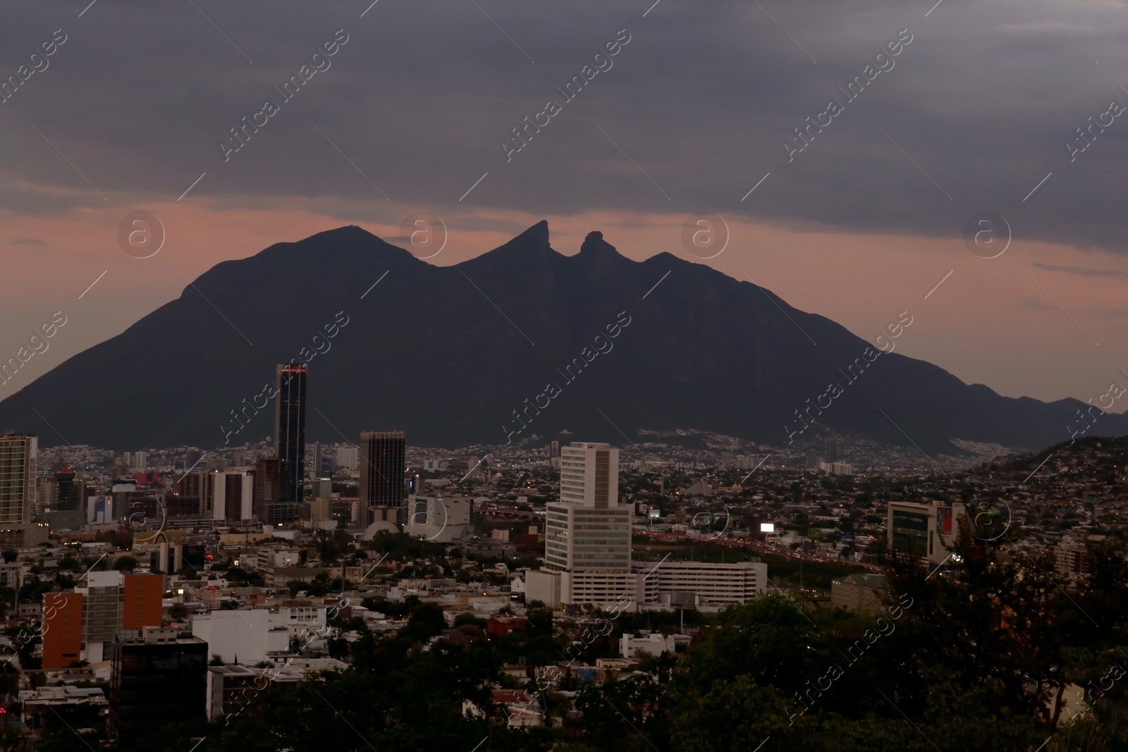 Photo of Picturesque view of sunset above big mountains and city