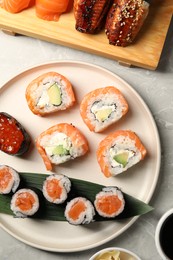 Delicious sushi rolls on light grey marble table, flat lay