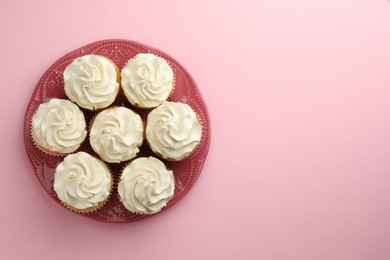 Photo of Tasty vanilla cupcakes with cream on pink background, top view. Space for text